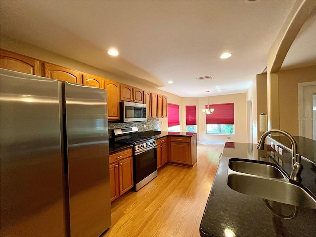 16405 SW 14th Avenue Rd, Ocala, FL 34473 - kitchen with appliances with stainless steel finishes, a sink, light wood-style floors, dark countertops, and backsplash