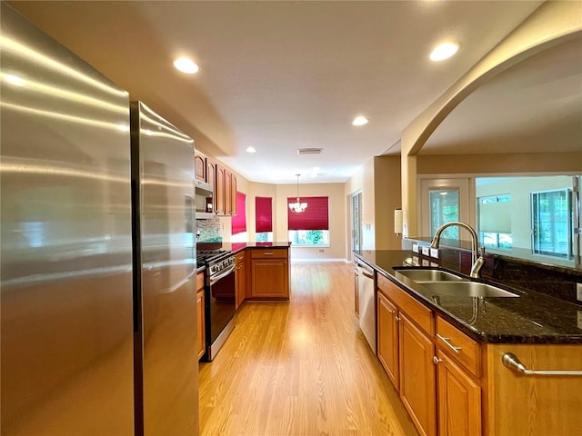 16405 SW 14th Avenue Rd, Ocala, FL 34473 - kitchen featuring stainless steel appliances, a sink, light wood finished floors, a peninsula, and arched walkways