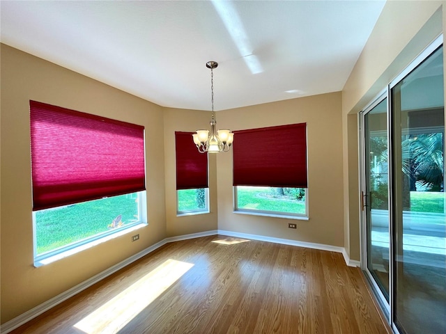16405 SW 14th Avenue Rd, Ocala, FL 34473 - empty room featuring wood finished floors, plenty of natural light, a chandelier, and baseboards