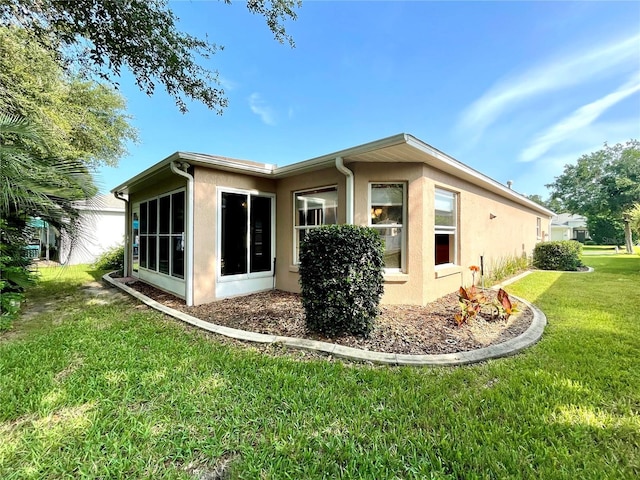 16405 SW 14th Avenue Rd, Ocala, FL 34473 - view of home's exterior featuring stucco siding, a lawn, and a sunroom