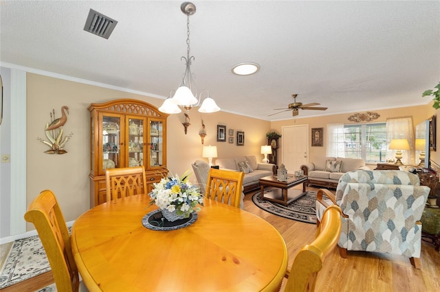 8420 SW 93rd Ln Unit E, Ocala, FL 34476 - dining space with light wood-style flooring, ornamental molding, a ceiling fan, a textured ceiling, and a chandelier