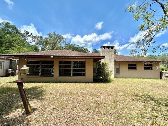 20100 SW 95th St, Dunnellon, FL 34431 - back of house with stucco siding, a lawn, and a chimney