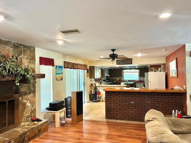 20100 SW 95th St, Dunnellon, FL 34431 - living area with light wood-style flooring, a stone fireplace, and a ceiling fan