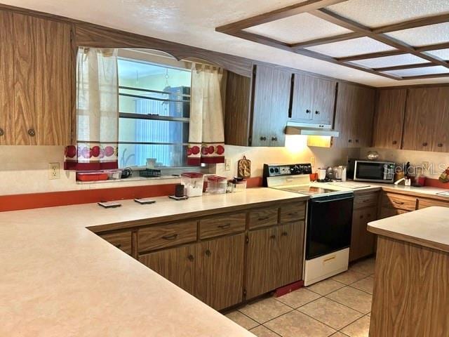 20100 SW 95th St, Dunnellon, FL 34431 - kitchen featuring range with electric stovetop, stainless steel microwave, under cabinet range hood, and light countertops