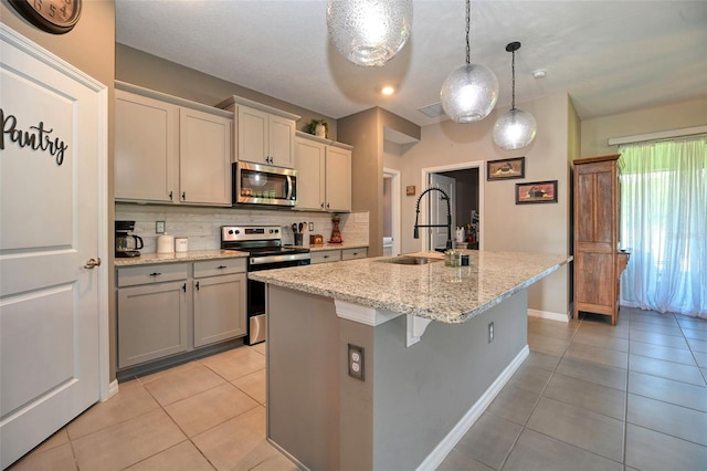 6405 SW 88th Loop, Ocala, FL 34476 - kitchen with stainless steel appliances, light tile patterned flooring, decorative backsplash, and an island with sink