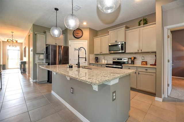 6405 SW 88th Loop, Ocala, FL 34476 - kitchen featuring appliances with stainless steel finishes, light tile patterned floors, tasteful backsplash, and an island with sink