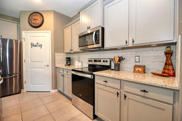 6405 SW 88th Loop, Ocala, FL 34476 - kitchen featuring appliances with stainless steel finishes, decorative backsplash, light tile patterned floors, and light stone counters
