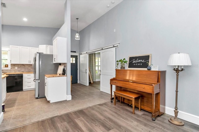 12080 SE Sunset Harbor Rd, Weirsdale, FL 32195 - kitchen featuring dishwasher, a high ceiling, light countertops, white cabinetry, and decorative backsplash