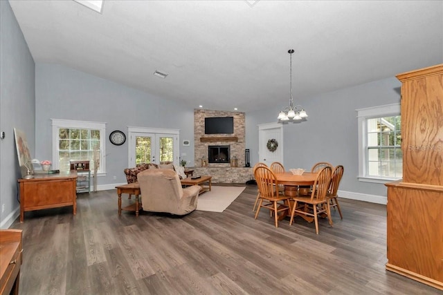 12080 SE Sunset Harbor Rd, Weirsdale, FL 32195 - dining area featuring dark wood-style flooring, healthy amount of natural light, a stone fireplace, a chandelier, and high vaulted ceiling