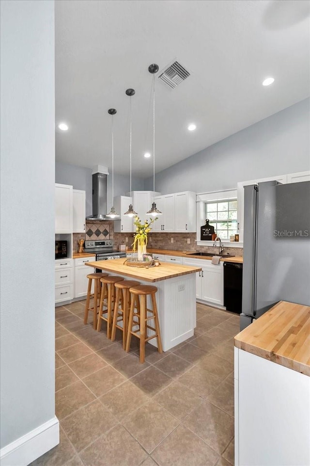 12080 SE Sunset Harbor Rd, Weirsdale, FL 32195 - kitchen featuring wall chimney range hood, appliances with stainless steel finishes, butcher block countertops, decorative backsplash, and recessed lighting