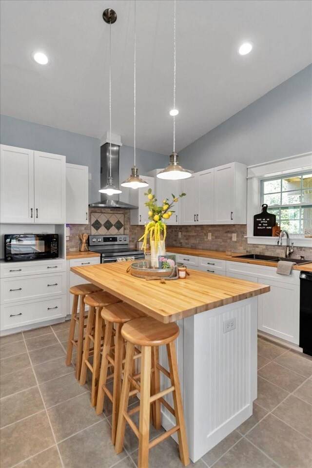 12080 SE Sunset Harbor Rd, Weirsdale, FL 32195 - kitchen featuring butcher block counters, wall chimney exhaust hood, light tile patterned floors, a center island, and recessed lighting