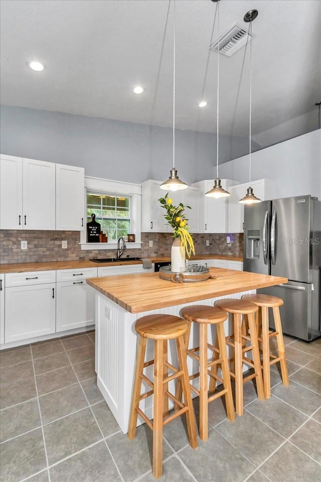 12080 SE Sunset Harbor Rd, Weirsdale, FL 32195 - kitchen with wooden counters, stainless steel fridge, light tile patterned flooring, tasteful backsplash, and recessed lighting