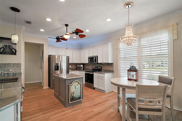 8772 SE 130th Loop, Summerfield, FL 34491 - kitchen featuring appliances with stainless steel finishes, ceiling fan, crown molding, white cabinetry, and light wood finished floors