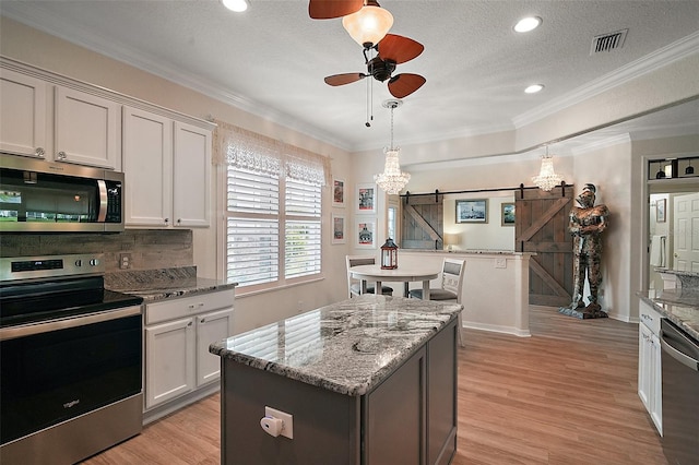 8772 SE 130th Loop, Summerfield, FL 34491 - kitchen featuring stainless steel appliances, ceiling fan, light wood-style flooring, a barn door, and light stone countertops