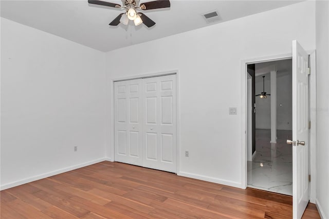 14550 SW 61st Ct, Ocala, FL 34473 - unfurnished bedroom featuring wood finished floors, baseboards, a closet, ceiling fan, and ensuite bathroom