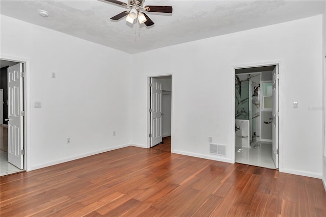 14550 SW 61st Ct, Ocala, FL 34473 - unfurnished bedroom featuring wood finished floors, a walk in closet, baseboards, and ensuite bathroom