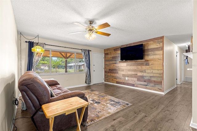 5005 NE 22nd Ave, Ocala, FL 34479 - living room featuring wood walls, a ceiling fan, a textured ceiling, wood finished floors, and baseboards