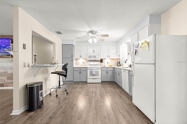 5005 NE 22nd Ave, Ocala, FL 34479 - kitchen featuring white appliances, gray cabinets, ceiling fan, a sink, and light wood-type flooring