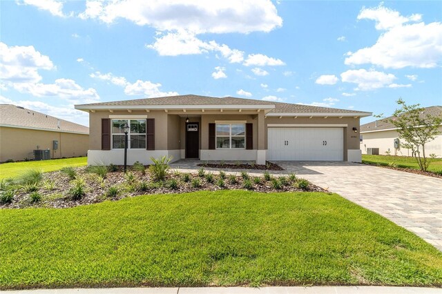 10562 SW 96th Lane Rd, Ocala, FL 34481 - view of front of house featuring stucco siding, a garage, cooling unit, decorative driveway, and a front yard