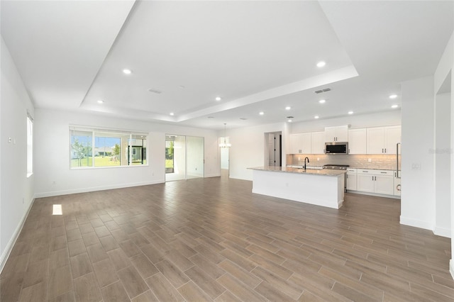 10562 SW 96th Lane Rd, Ocala, FL 34481 - unfurnished living room featuring a raised ceiling, a sink, recessed lighting, baseboards, and wood finished floors
