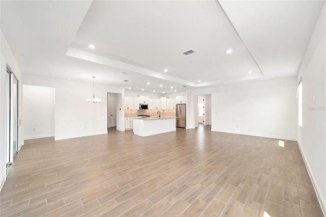 10562 SW 96th Lane Rd, Ocala, FL 34481 - unfurnished living room with a raised ceiling, a chandelier, recessed lighting, baseboards, and light wood-type flooring
