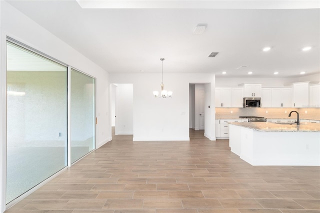10562 SW 96th Lane Rd, Ocala, FL 34481 - kitchen featuring stainless steel microwave, a chandelier, baseboards, tasteful backsplash, and white cabinetry