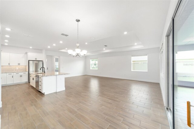 10562 SW 96th Lane Rd, Ocala, FL 34481 - kitchen featuring stainless steel appliances, a chandelier, open floor plan, backsplash, and white cabinetry