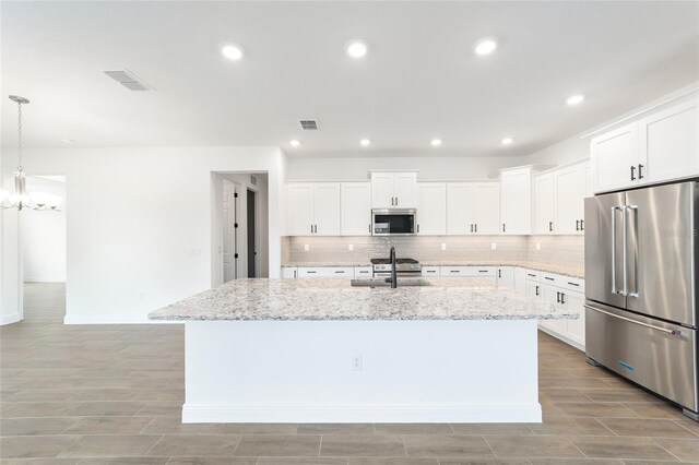10562 SW 96th Lane Rd, Ocala, FL 34481 - kitchen with appliances with stainless steel finishes, backsplash, a sink, a kitchen island with sink, and white cabinetry