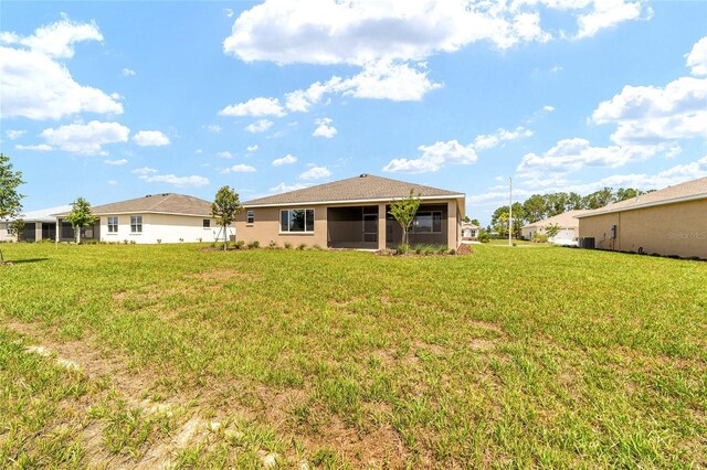 10562 SW 96th Lane Rd, Ocala, FL 34481 - rear view of property featuring a sunroom, a lawn, and central AC