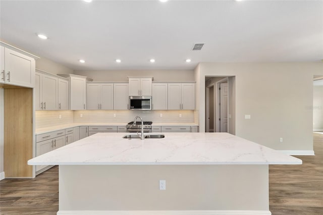 9865 SW 105th Ct, Ocala, FL 34481 - kitchen featuring a sink, stainless steel microwave, decorative backsplash, an island with sink, and wood finished floors