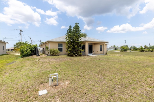 3019 NW Juanita Pl, Cape Coral, FL 33993 - back of house with stucco siding and a lawn