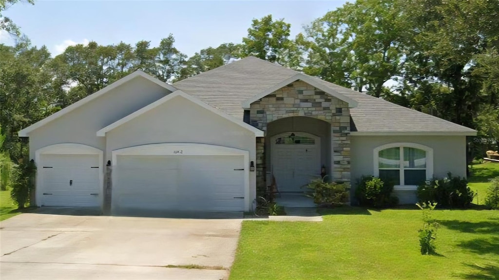 11412 SW 51st Cir, Ocala, FL 34476 - view of front of property with a garage, driveway, a front yard, stone siding, and stucco siding