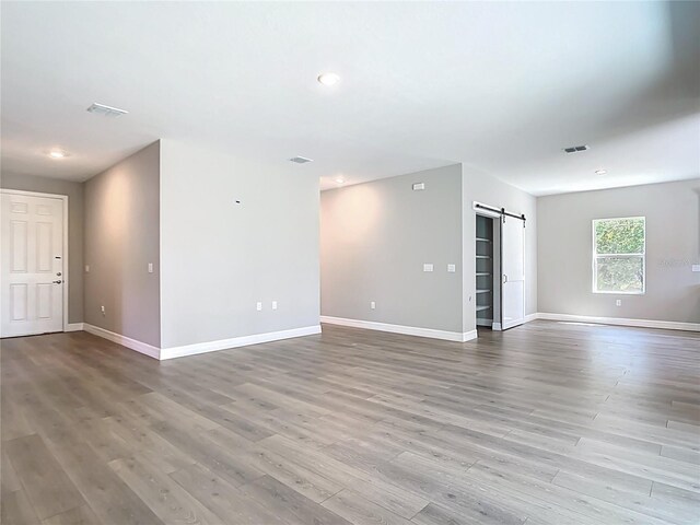 3018 Oceanside St, North Port, FL 34286 - empty room featuring a barn door, wood finished floors, baseboards, and recessed lighting
