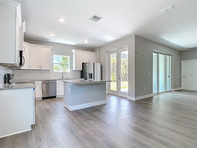 3018 Oceanside St, North Port, FL 34286 - kitchen featuring stainless steel appliances, a center island, a sink, decorative backsplash, and white cabinetry