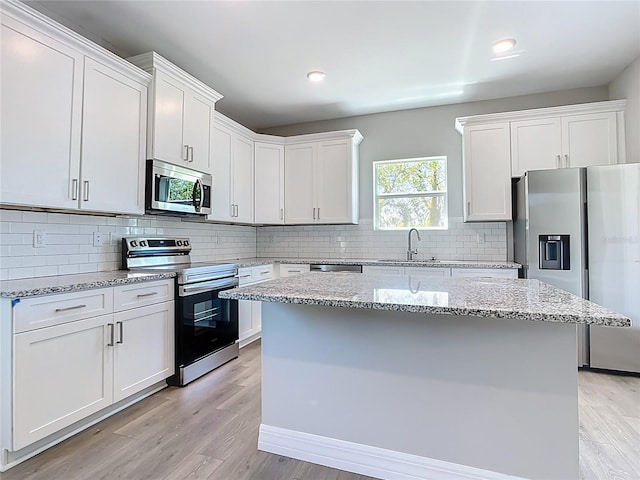 3018 Oceanside St, North Port, FL 34286 - kitchen with stainless steel appliances, a sink, a kitchen island, white cabinetry, and recessed lighting
