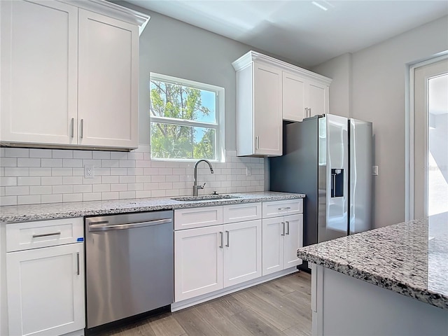 3018 Oceanside St, North Port, FL 34286 - kitchen with appliances with stainless steel finishes, a sink, light wood-type flooring, white cabinetry, and tasteful backsplash