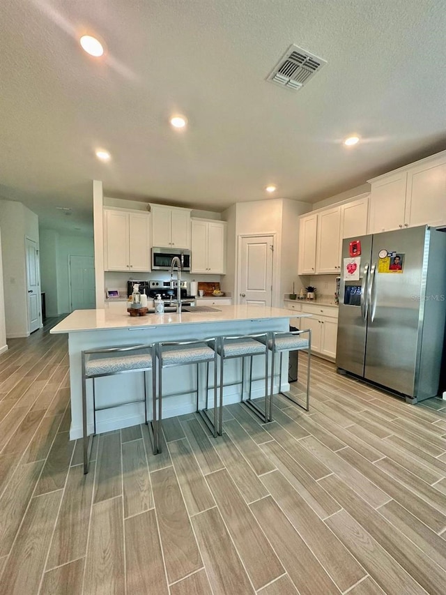 9253 SW 58th Cir, Ocala, FL 34476 - kitchen with appliances with stainless steel finishes, wood tiled floors, recessed lighting, a breakfast bar, and light countertops