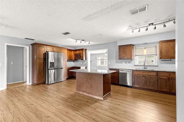 6989 SE 52nd Pl, Ocala, FL 34472 - kitchen with appliances with stainless steel finishes, rail lighting, light wood-style floors, a sink, and a center island