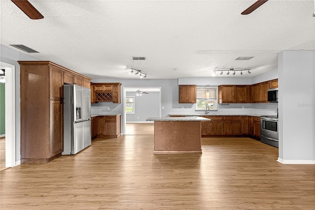 6989 SE 52nd Pl, Ocala, FL 34472 - kitchen featuring ceiling fan, appliances with stainless steel finishes, track lighting, light wood finished floors, and a textured ceiling