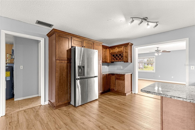 6989 SE 52nd Pl, Ocala, FL 34472 - kitchen featuring stainless steel fridge with ice dispenser, light wood-style flooring, electric water heater, brown cabinetry, and a textured ceiling