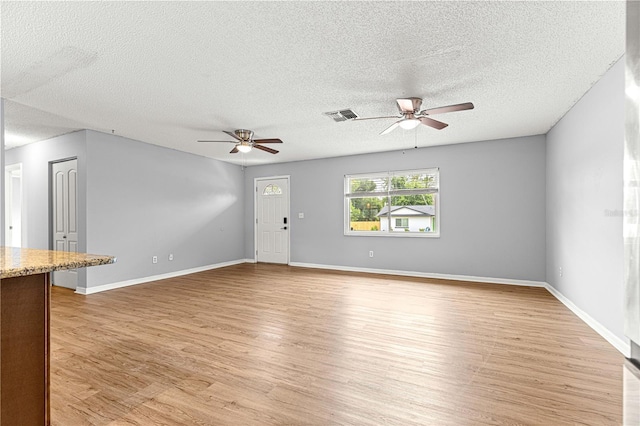 6989 SE 52nd Pl, Ocala, FL 34472 - unfurnished living room with a ceiling fan, light wood-style floors, a textured ceiling, and baseboards