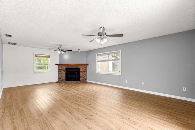 6989 SE 52nd Pl, Ocala, FL 34472 - unfurnished living room with a textured ceiling, light wood-style flooring, ceiling fan, baseboards, and a brick fireplace