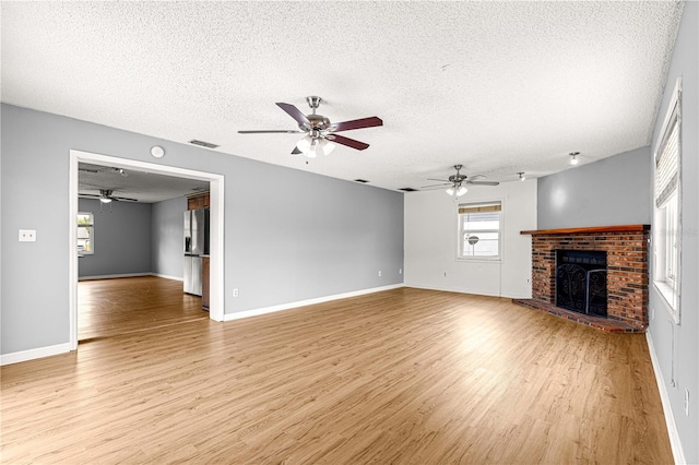 6989 SE 52nd Pl, Ocala, FL 34472 - unfurnished living room featuring a brick fireplace, a textured ceiling, ceiling fan, and healthy amount of natural light