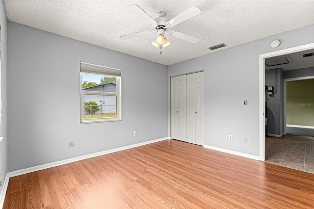 6989 SE 52nd Pl, Ocala, FL 34472 - unfurnished bedroom with light wood-style floors, a textured ceiling, a closet, baseboards, and ceiling fan