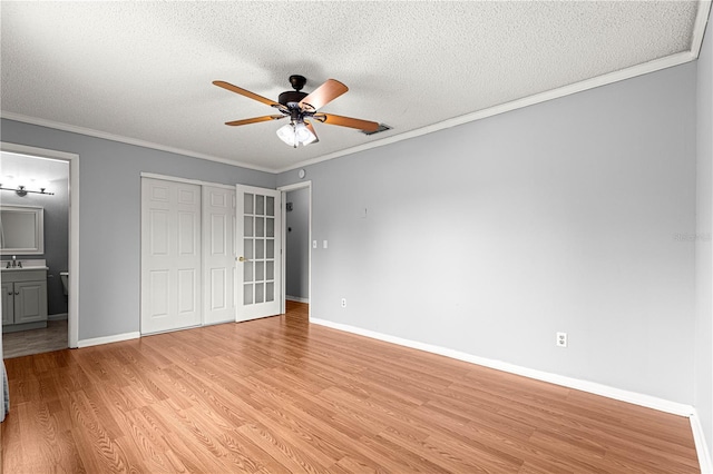 6989 SE 52nd Pl, Ocala, FL 34472 - unfurnished bedroom featuring light wood-type flooring, a textured ceiling, baseboards, connected bathroom, and ornamental molding