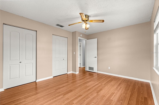 6989 SE 52nd Pl, Ocala, FL 34472 - unfurnished bedroom with multiple closets, light wood-style flooring, a textured ceiling, baseboards, and ceiling fan