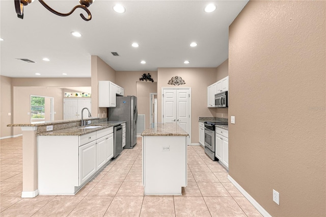 8961 SE 130th Loop, Summerfield, FL 34491 - kitchen with appliances with stainless steel finishes, a sink, a kitchen island, white cabinets, and recessed lighting