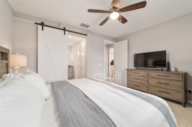 5651 NW 40th Pl, Ocala, FL 34482 - bedroom with a barn door, light colored carpet, ensuite bathroom, ceiling fan, and baseboards