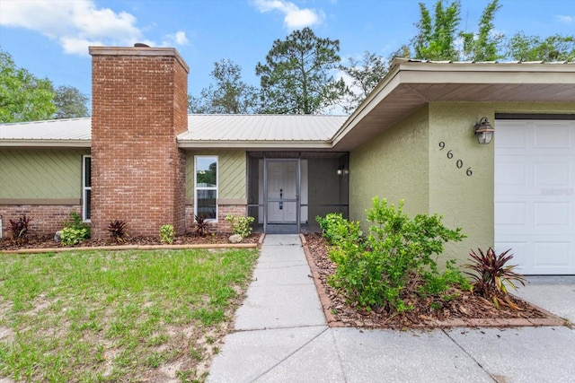 9606 N Caressa Way, Citrus Springs, FL 34434 - view of exterior entry with a chimney, an attached garage, stucco siding, and metal roof