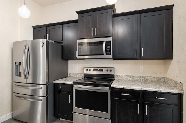10910 SW 41st Ave, Ocala, FL 34476 - kitchen with stainless steel appliances, decorative light fixtures, and dark cabinetry